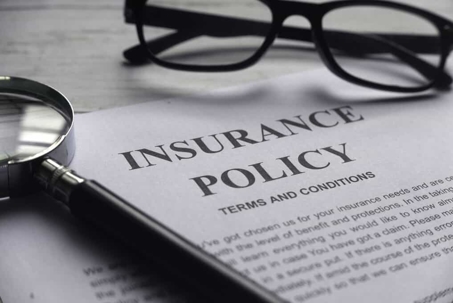 Insurance policy document with reading glasses and a magnifying glass